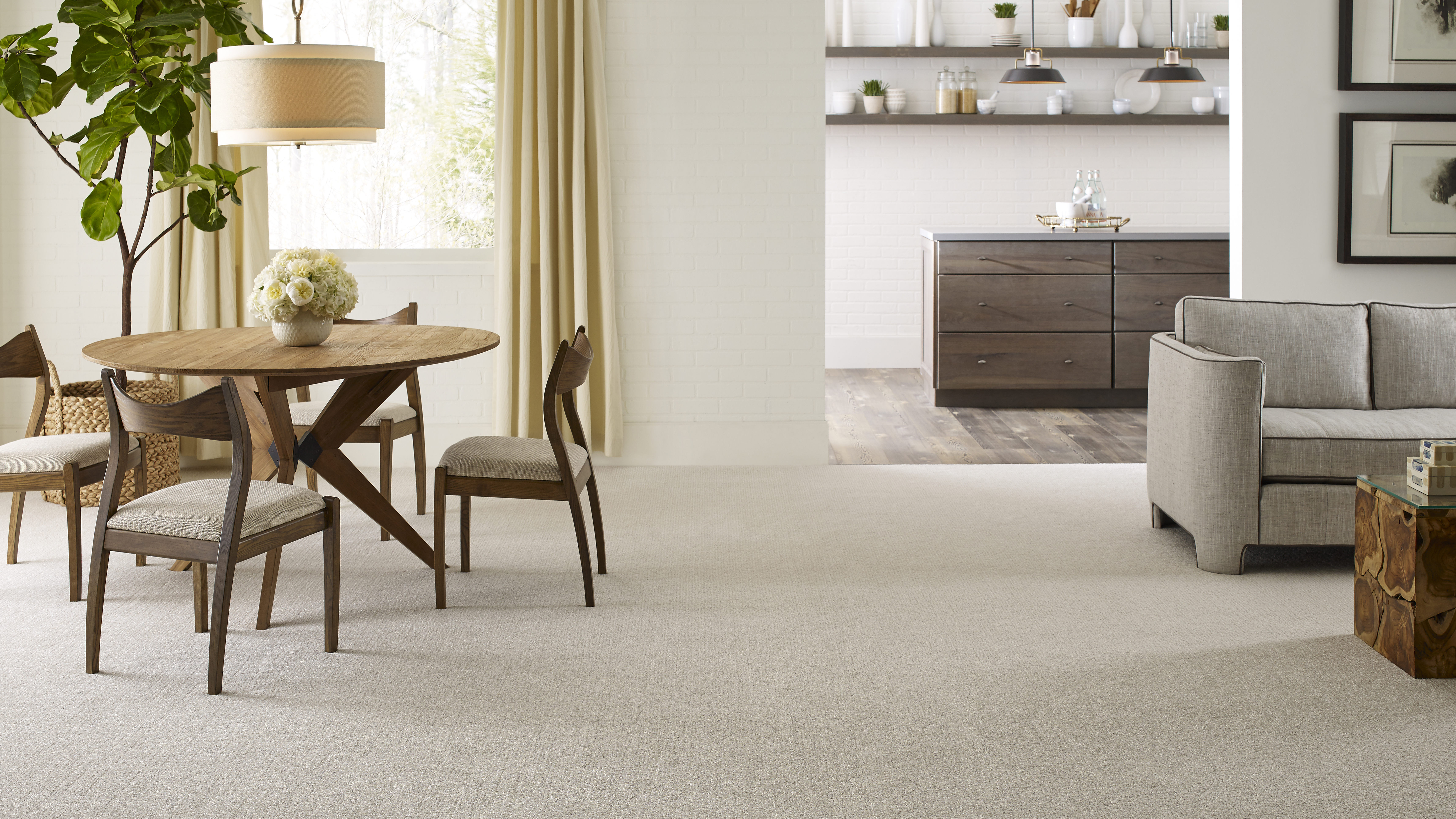 carpet flooring below a table with chairs and a grey couch 